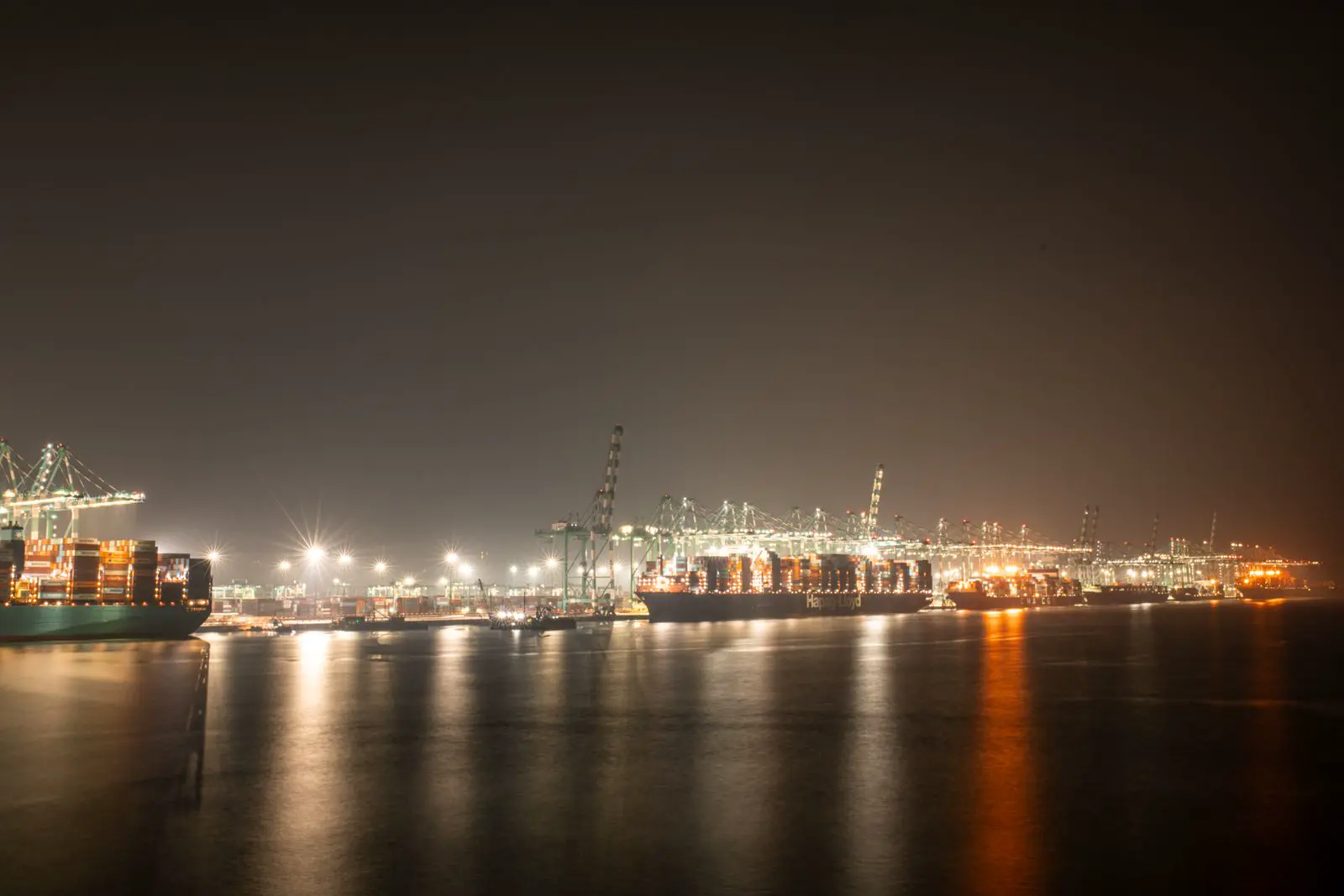 Container port lit up at night across calm water