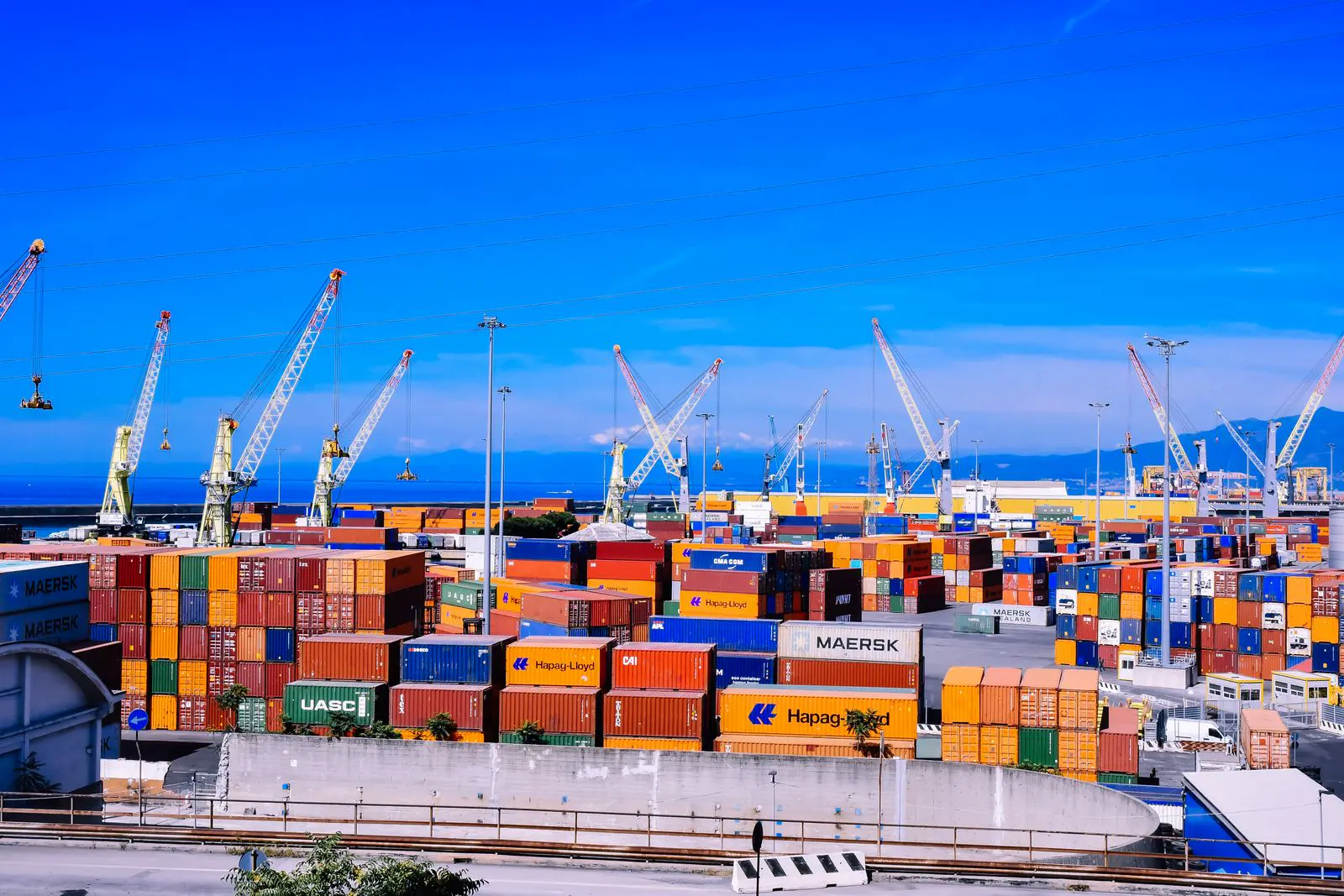 Port with stacked containers and cranes on a clear day